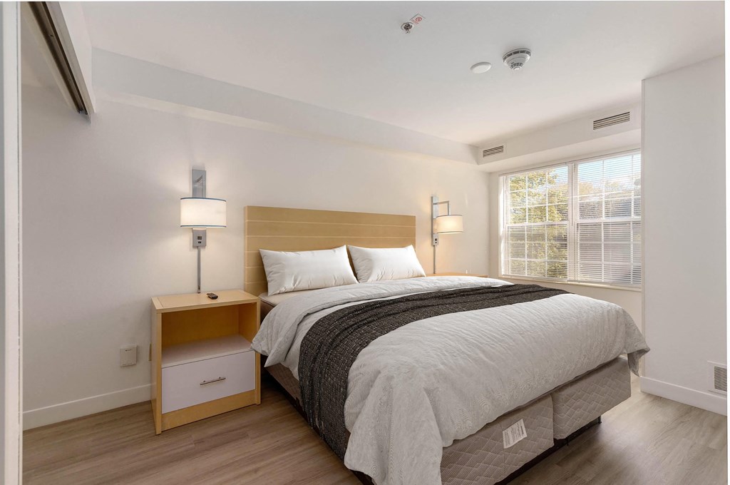 a bedroom with a bed and two lamps and a window